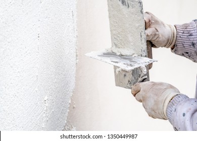 Construction worker plastering and smoothing concrete wall with cement.