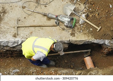 Construction Worker With Pneumatic Hammer Drill , Pick And Shovel To Repair  Water And Sewer Pipes