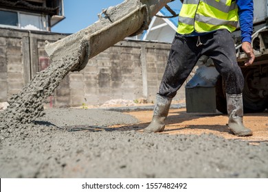 Ein Bauarbeiter, der auf dem Straßenbaugelände einen feuchten Beton gießt