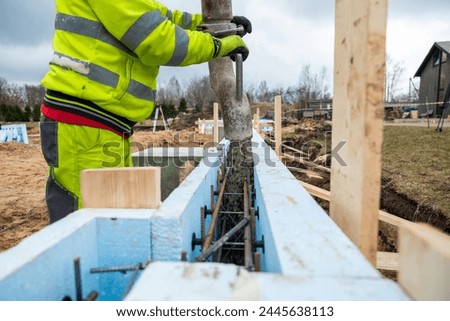 Construction Worker Precisely Operating Concrete Pump at New Building Site Foundations