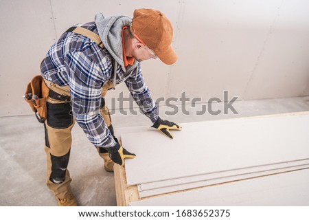 Construction Worker Preparing Building Materials. Drywall, Sheetrock and Plywood Boards. Construction Industry Theme.