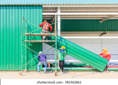 Construction worker in protective uniform and protective helmet install a steel sheet metal profiles in a construction site