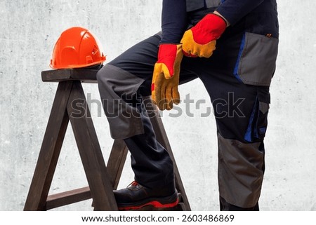 Construction worker, puts on an protective work gloves. Builder in protective workwear.