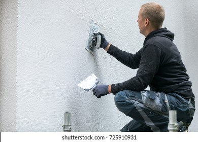construction worker putting decorative plaster on house exterior