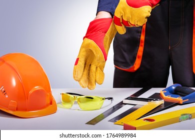 Construction Worker Putting On Protective Gloves. Composition With Safety Equipment And Tools. Copy Space.