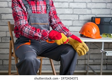 Construction Worker Putting On Protective Gloves At Workplace.