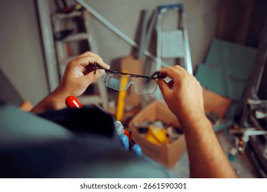 
Construction Worker Putting on Protective Glasses for Work. Specialist using  personal protective equipment on worksite