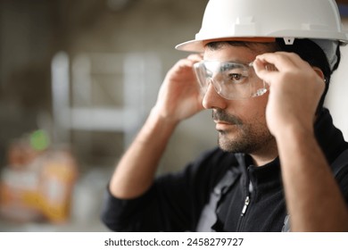 Construction worker putting protective eyeglasses in a house under renovation
