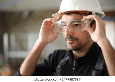 Construction worker putting protective glasses before work in a house under reform