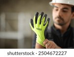 Construction worker putting protective glove before work in a house under reform