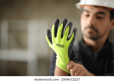 Construction worker putting protective glove before work in a house under reform - Powered by Shutterstock