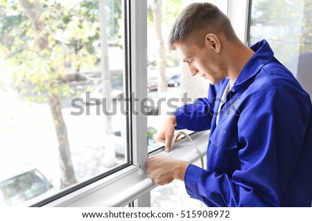 Construction worker putting sealing foam tape on window in house