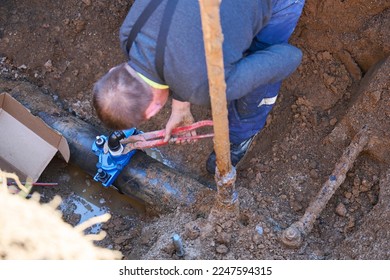 Construction worker, repairing a broken water pipe.
Construction site with new Water Pipes in the ground. Plumber work repair water line connect. - Shutterstock ID 2247594315