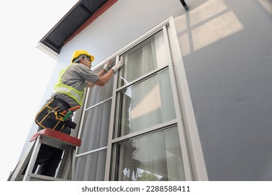 Construction worker repairing the sliding window. Open cap of adjust rail wheel.