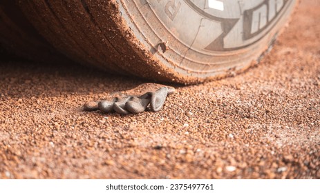 A construction worker rubber glove is placed on dirt ground under the heavy vehicle wheel road at construction worksite. Transportation accident scene concept.