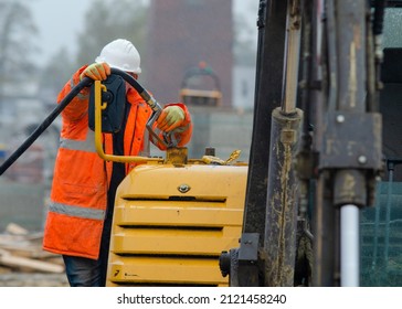 Construction worker in safety gloovs filling excavator with diesel fuel on building site