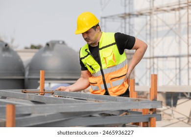 Construction worker in safety vest and hard hat inspecting structure at building site, experiencing low back pain. Concept of occupational health and safety. - Powered by Shutterstock