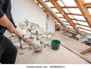 Construction Worker With A Shovel After Demolishing  A Brick Wall In A Private Home.