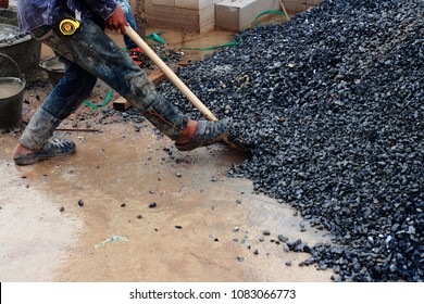 Construction Worker Shoveling Agregrate Stone In A Construction Site. Worker Without Safety Equipment. Working In An Unsafe Environment.