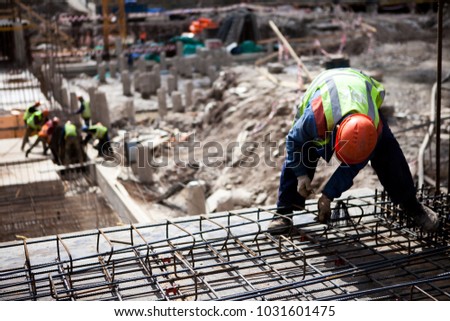 Construction worker. Сoncrete construction site: pillar, steel rebar. Contractor worker works with concrete slab steel cage. Construction site with builder worker. Concrete slab construction.