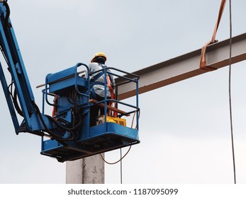 construction worker at construction site using lifting boom machinery