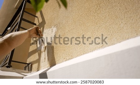 Construction worker skillfully applies plaster to a building facade, smoothing the surface with a trowel.