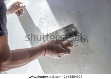 Construction worker skillfully applies plaster to a wall using a trowel, creating a smooth surface during a home renovation or construction project