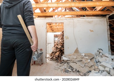 Construction Worker With A Sledge Hammer After Demolishing  A Brick Wall In A Private Home.