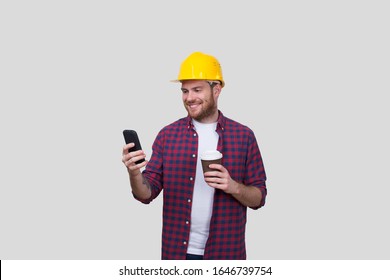 Construction Worker Smiling Chatting on the Phone And Holding Coffee to go Cup. Yellow Helmet