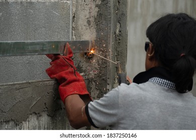 Construction Worker : Stand With Your Back And Connect The Steel To The Machine Of The Wall Post. With Sparks Coming Out Of Welding