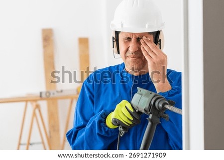Construction worker suffering accident in an eye working with a electric drill without protection glasses at building