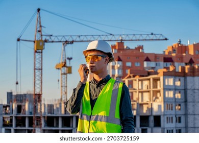 A construction worker talking on a cell phone in front of a construction site