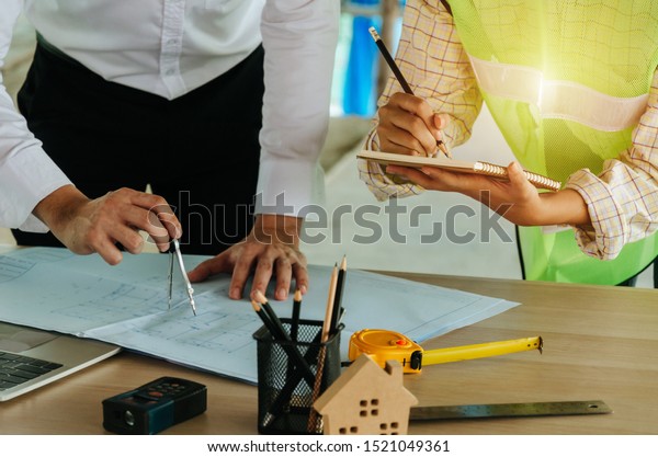 construction worker team drawing and planning\
about building plan with blueprint, construction tools on\
conference table at construction site, contractor, business,\
industry and construction\
concept