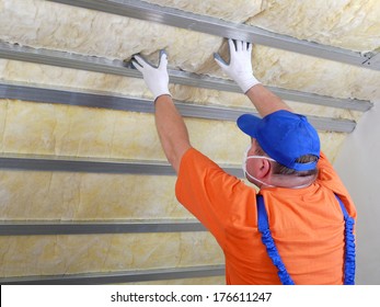 Construction worker thermally insulating house attic with mineral wool - Shutterstock ID 176611247