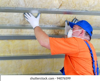 Construction worker thermally insulating house attic with mineral wool - Shutterstock ID 94076599
