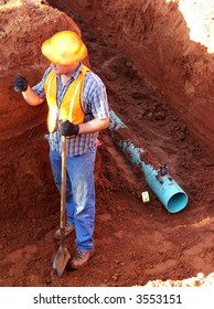 Construction Worker In A Trench With A Pipe