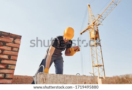 Construction worker in uniform and safety equipment have job on building.