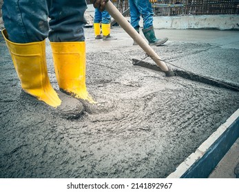 Construction worker uses bullfloat to flatten cement mortar screed. Concrete works on construction site. Cast-in-place work using trowels.  - Shutterstock ID 2141892967