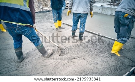 Construction worker uses bullfloat to spread cement mortar screed. Concrete works on construction site. Cast-in-place concrete works. Contractors spread grout using trowel