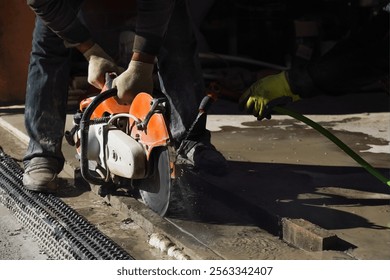 Construction worker uses a cutting tool on a concrete surface during a repair project. 