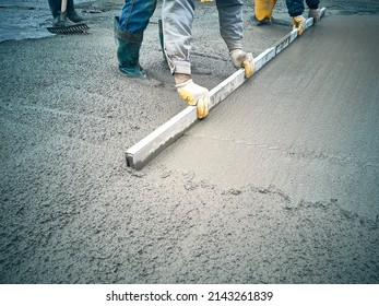 Construction worker uses trowel to level cement mortar screed. Concrete works on construction site. Cast-in-place work using trowels. 