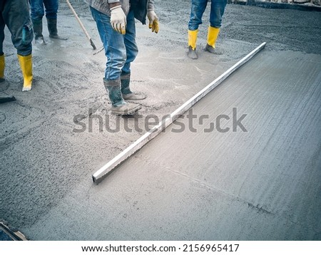 Construction worker uses trowel to level cement mortar screed. Concrete works on construction site. Cast-in-place work using trowels. 