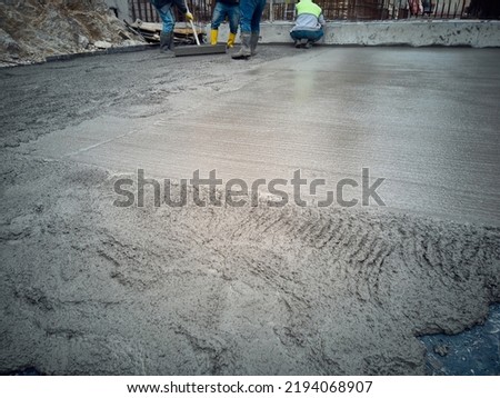 Construction worker uses trowel to level cement mortar screed. Concrete works on construction site. Cast-in-place work using trowels. 