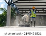 A construction worker using concrete polishing machine or polishing marble floor at construction site. Concrete floors.