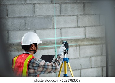 Construction worker is using cross-line laser level meter with line green beam to mark the floor in construction site. Tools for measuring distances.