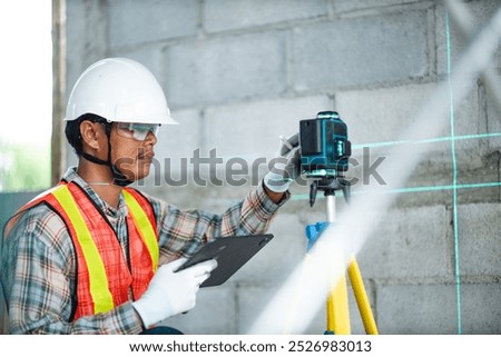 Construction worker is using cross-line laser level meter with line green beam to mark the floor in construction site. Tools for measuring distances.