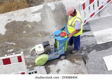 construction worker using cutting  pavement machine and large jackhammer in city street