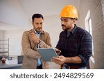 Construction worker using digital tablet with home owner during renovating process. 