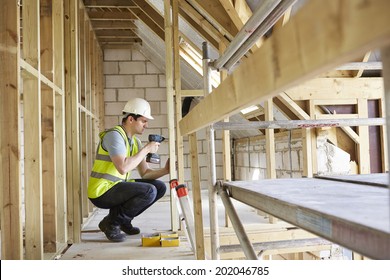 Construction Worker Using Drill On House Build