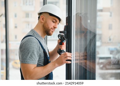Construction worker using drill while installing window indoors - Shutterstock ID 2142914059